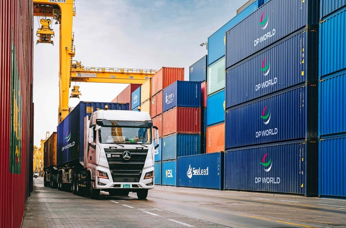DP World truck driving between stacks of shipping containers at a port